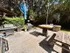 Inviting outdoor patio with grills and rustic picnic table, surrounded by lush greenery and trees.