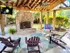 Inviting outdoor lounge with cozy Adirondack chairs, a charming brick fireplace, and vibrant greenery under a stylish wooden pergola.