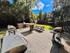 Charming outdoor patio with grills and wooden picnic table surrounded by lush greenery, perfect for gatherings and relaxation.