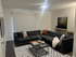 Chic living room with a modern gray sectional sofa, stylish geometric rug, and elegant dining area, perfect for cozy gatherings.