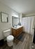 Elegant bathroom with modern vanity, sleek fixtures, and a cozy ambiance, highlighting a stylish shower curtain and dark wood flooring.