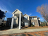 Charming apartment building with classic brick facade, nestled in a serene setting under a clear blue sky.