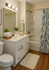 Inviting bathroom with a modern vanity, elegant lighting, and a stylish leafy shower curtain.