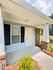 Charming front porch with elegant brick accents and lush greenery, perfect for a warm welcome.
