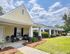 Charming single-story home with inviting front porch and well-maintained garden under a bright blue sky.