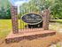 Welcoming entrance to Ashton Trace Apartments, featuring a charming brick sign set amidst lush greenery.
