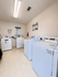 Bright and modern laundry room featuring multiple washers and dryers in a pristine, well-organized space.
