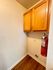 Charming utility nook with warm oak cabinets, vibrant fire extinguisher, and elegant hardwood floors, perfect for compact storage.
