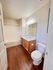 Bright modern bathroom featuring sleek wood flooring, large mirror, and pristine bathtub in a cozy apartment.