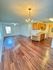 Inviting open-plan living space with elegant wooden flooring and a modern kitchen, enhanced by a chic chandelier.