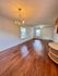 Elegant, sunlit room featuring polished hardwood floors, a classic chandelier, and large windows providing ample natural light.