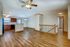 Spacious open-concept living area featuring elegant wood flooring, modern ceiling fan, and a cozy kitchen with wooden cabinetry.
