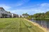 Charming lakeside townhouses with beautiful blue skies, lush green lawns, and serene water views.