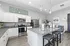 Chic open-concept kitchen featuring sleek granite countertops, stainless steel appliances, and modern pendant lighting, blending seamlessly into a cozy living area with stylish decor.