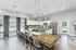 Bright and modern kitchen featuring a sleek dining area with transparent chairs, stylish pendant lighting, and a view of the outdoor pool.