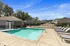 Inviting community pool area with modern waterfall feature, surrounded by sun lounges and charming suburban homes in the background.