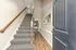 Inviting entrance with elegant carpeted staircase and stylish hallway, leading to a bright living area.