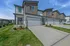 Modern townhouse exterior with sleek design, double garage, and well-manicured lawns against a clear blue sky, showcasing contemporary living.