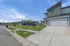 Modern suburban home with sleek driveway, spacious garage, and neatly landscaped front yard, set under a clear blue sky.