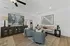Inviting living room with modern decor, featuring plush grey chairs, a cozy beige sofa, and elegant artwork. Accented by soft lighting and a stylish ceiling fan.