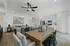 Bright, open-concept living and dining area with modern decor, stylish ceiling fan, and a contemporary kitchen with sleek white cabinets.