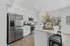 Bright, modern kitchen with sleek stainless steel appliances, elegant white cabinetry, and a cozy breakfast bar with stylish stools.