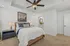 Elegant bedroom with a cozy double bed, stylish ceiling fan, and a tranquil painting above, leading to a modern ensuite bathroom.