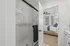 Inviting modern bedroom with plush bedding visible through a sleek glass shower door, highlighting stylish design elements and natural lighting.
