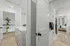 Bright modern hallway featuring a pristine laundry area with a washing machine, elegantly designed doors, and a glimpse into a cozy bedroom.