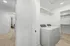 Bright and spacious laundry room with modern washer and dryer, adjacent to a cozy carpeted hallway leading to a well-lit living area.