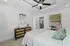 Chic bedroom featuring elegant ceiling fan, stylish dresser with mirror, and inviting decor in a serene setting.