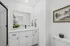 Elegant bathroom with a sleek white vanity, modern black fixtures, and a framed artwork enhancing the serene ambiance.