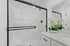 Elegant modern bathroom featuring a stylish glass shower enclosure, pristine white tiles, and a sleek vanity with a lush orchid arrangement.