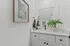 Chic bathroom with modern vanity, elegant framed art, and lush greenery enhancing a serene atmosphere.