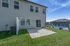 Charming apartment exterior with a private patio, lush green lawn, and access to a sparkling community pool under clear blue skies.