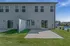 Charming modern apartment exterior featuring sleek siding, private fenced patio, and lush green lawn under a clear blue sky.