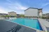 Inviting outdoor swimming pool with sleek lounge chairs and umbrellas, perfect for relaxing under clear blue skies.