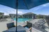 Inviting outdoor swimming pool area with modern lounge chairs, surrounded by elegant community buildings under a clear blue sky.