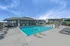Inviting outdoor pool area with modern lounge chairs and shaded seating under a bright blue sky, perfect for relaxation and leisure.