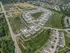 Aerial view of a modern suburban housing development with neatly arranged homes, lush green spaces, and winding roads, offering a tranquil and community-focused living environment.