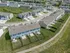 Aerial view of a charming suburban neighborhood with rows of townhouses featuring fenced backyards, lush green spaces, and a communal swimming pool.