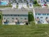 Charming aerial view of modern townhouses with private decks, lush green lawns, and a refreshing pool, perfect for vibrant community living.