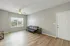 Bright and welcoming living room with sleek wood flooring and modern black sofa under a ceiling fan, complemented by natural light from a large window.