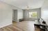 Bright and airy apartment showcasing a spacious living room with elegant wood flooring, a modern ceiling fan, and a large window inviting natural light.