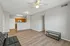 Bright and inviting open-concept living space featuring sleek wood flooring, a modern ceiling fan, and a cozy kitchen with warm wooden cabinetry.