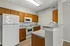 Modern kitchen featuring elegant wooden cabinetry, sleek countertops, and essential white appliances in a bright, open layout.