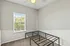 Bright bedroom with large window, ceiling fan, and a modern black bed frame, offering a serene and cozy living space.