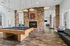 Chic recreation room with elegant wood flooring, featuring a modern pool table, cozy fireplace, and stylish lounge area.