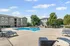 Beautiful apartment complex featuring a pristine outdoor pool and ample lounge seating, surrounded by landscaped greenery for a relaxing retreat.