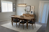 Chic dining room with elegant wooden table, modern light fixture, and stylish art decor, perfect for cozy gatherings.